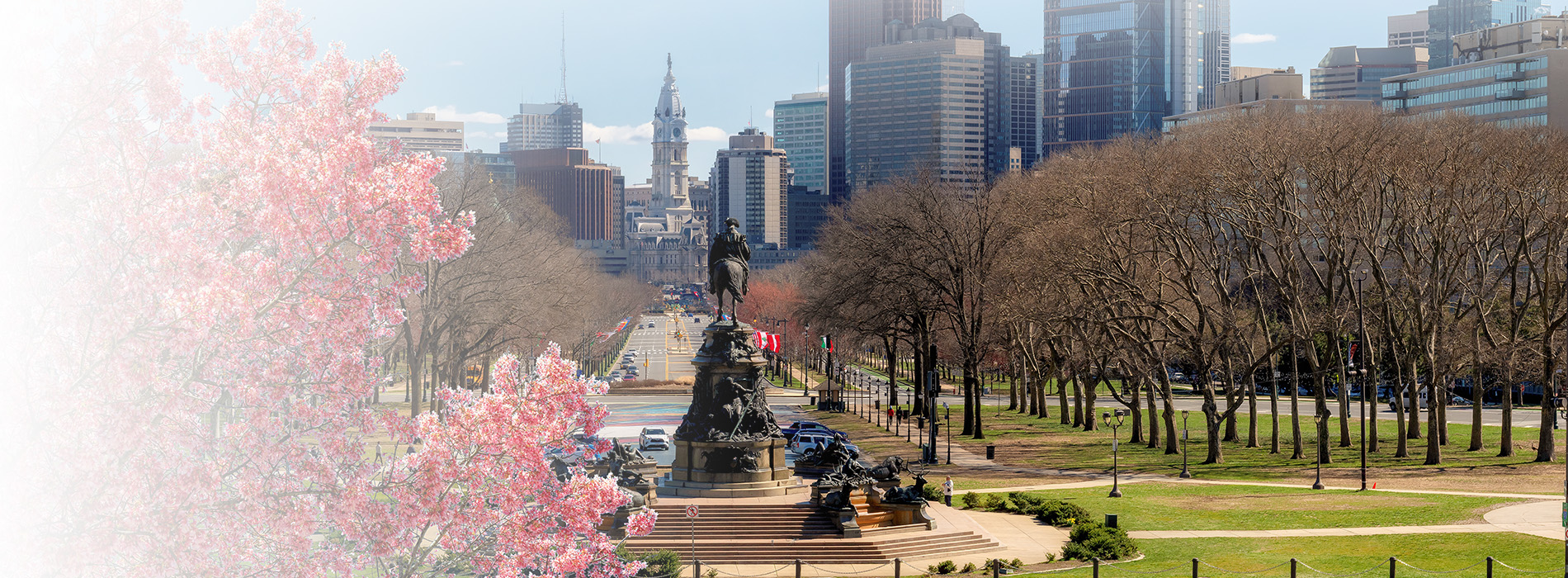 The image depicts a vibrant cityscape with a prominent park and a statue, set against a clear sky.